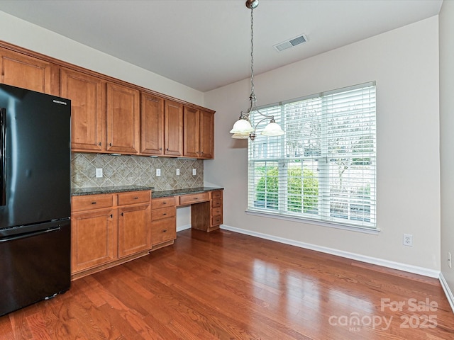 kitchen featuring visible vents, brown cabinets, freestanding refrigerator, and decorative backsplash