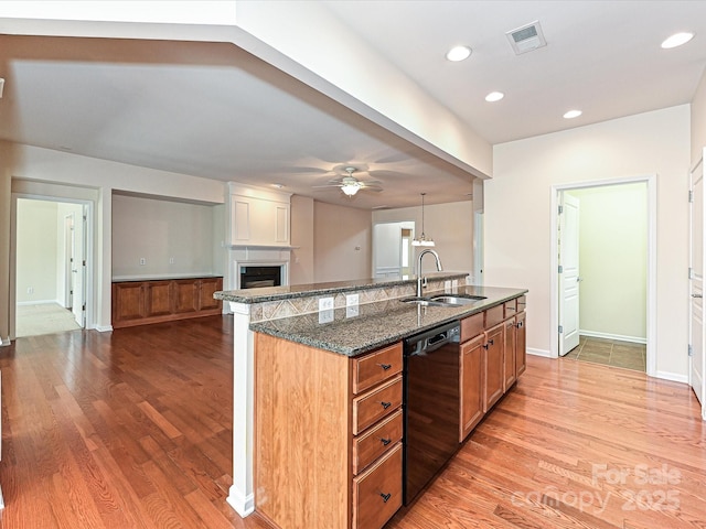 kitchen with visible vents, dishwasher, a fireplace, a ceiling fan, and a sink