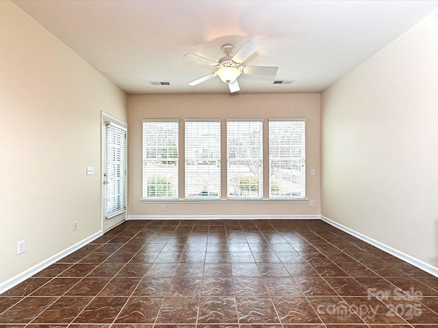 empty room featuring baseboards, visible vents, and ceiling fan