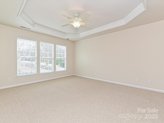 empty room with a ceiling fan, visible vents, crown molding, a raised ceiling, and light colored carpet