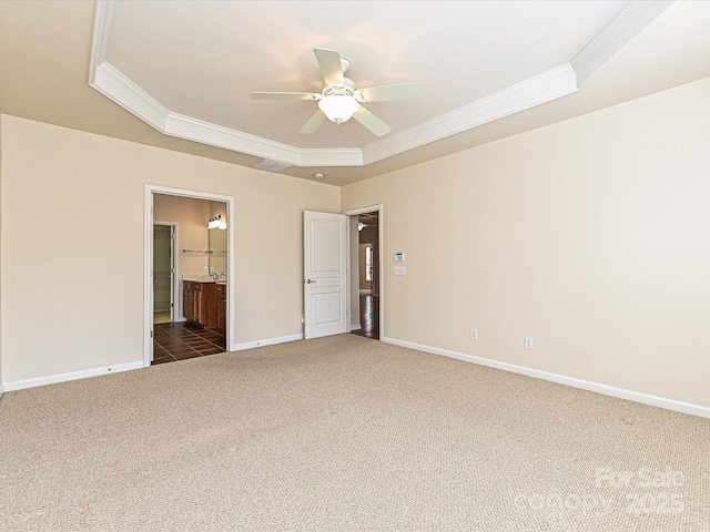 spare room featuring a raised ceiling, ornamental molding, a ceiling fan, carpet floors, and baseboards