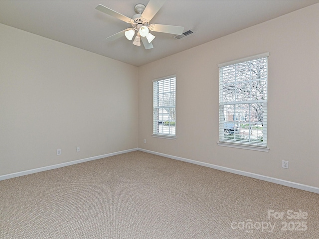 spare room featuring visible vents, light carpet, baseboards, and ceiling fan