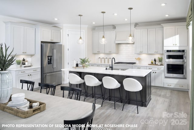 kitchen with a kitchen bar, light countertops, ornamental molding, stainless steel appliances, and a sink