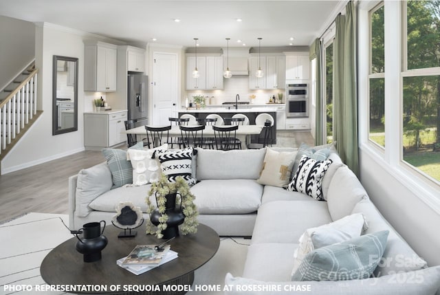 living area with stairs, crown molding, plenty of natural light, and light wood-style floors