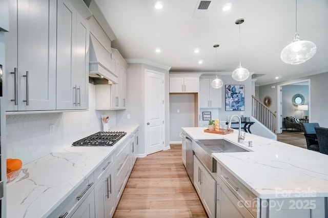 kitchen with a sink, light wood-style floors, recessed lighting, gas stovetop, and a center island with sink
