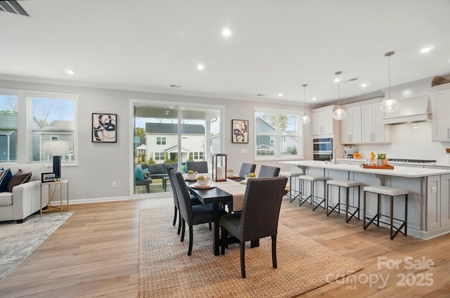 dining area featuring ornamental molding, recessed lighting, and light wood-style flooring