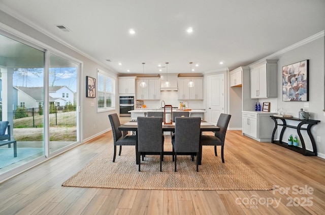 dining area featuring crown molding, light wood-style flooring, baseboards, and recessed lighting