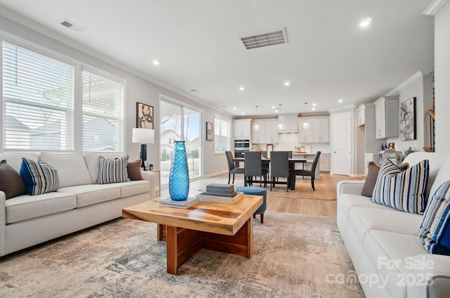 living room with recessed lighting, visible vents, ornamental molding, and light wood-style floors
