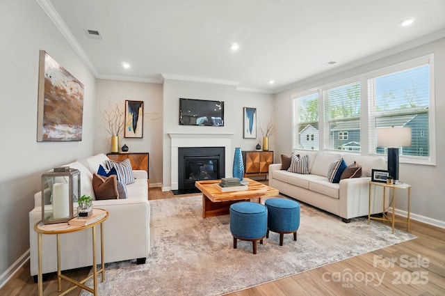 living room with recessed lighting, baseboards, a fireplace with flush hearth, wood finished floors, and ornamental molding