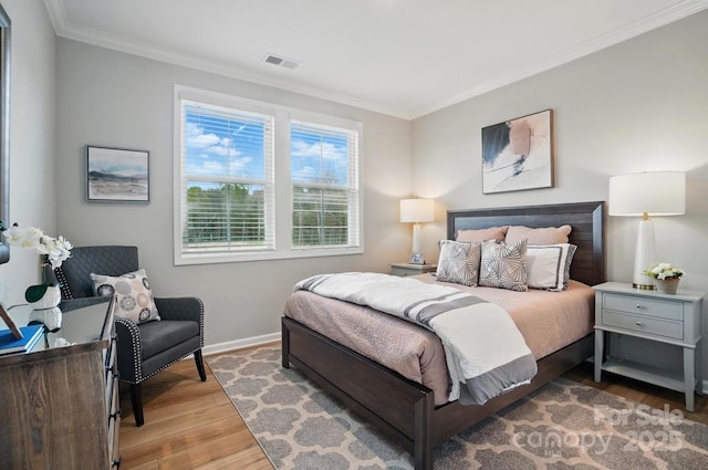 bedroom with baseboards, ornamental molding, wood finished floors, and visible vents