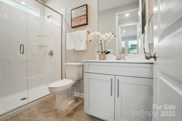 bathroom featuring vanity, tile patterned flooring, toilet, baseboards, and a stall shower
