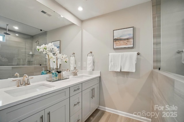 full bathroom with visible vents, a sink, a tile shower, and recessed lighting