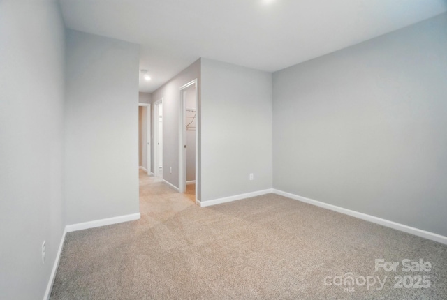 empty room featuring baseboards and light carpet