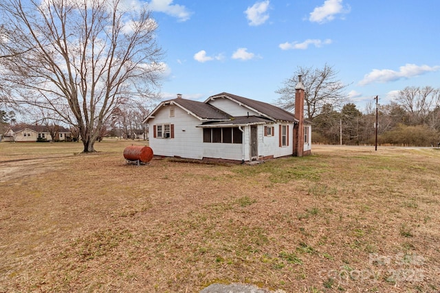 view of side of home featuring a lawn and a chimney