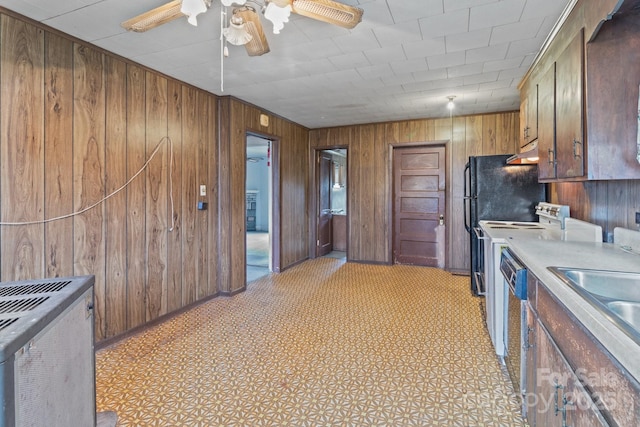 kitchen featuring a ceiling fan, a sink, wooden walls, light countertops, and dishwasher