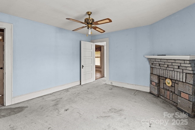 interior space featuring a brick fireplace, baseboards, carpet floors, and ceiling fan