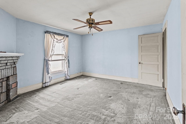 unfurnished room with baseboards, carpet, ceiling fan, and a fireplace