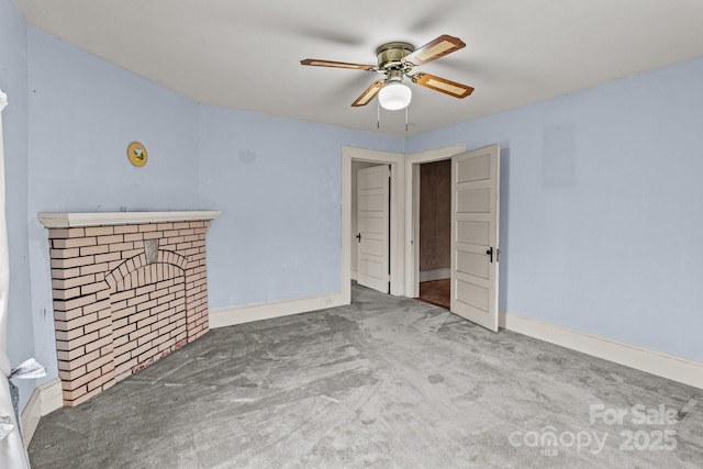 unfurnished room featuring ceiling fan, a fireplace, baseboards, and carpet