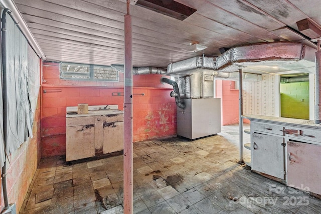 interior space with heating unit, tile patterned floors, and concrete block wall