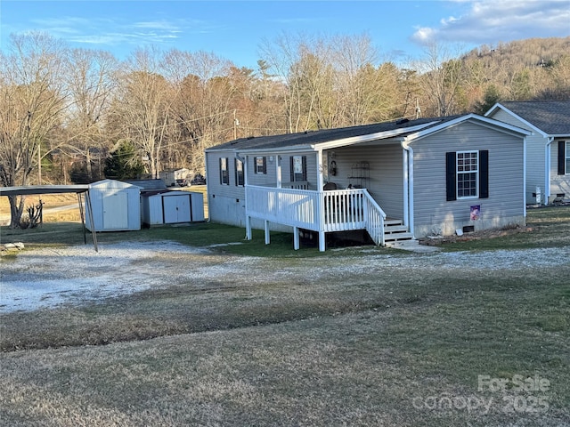 view of front of home with an outdoor structure, driveway, a wooden deck, a storage unit, and a front yard