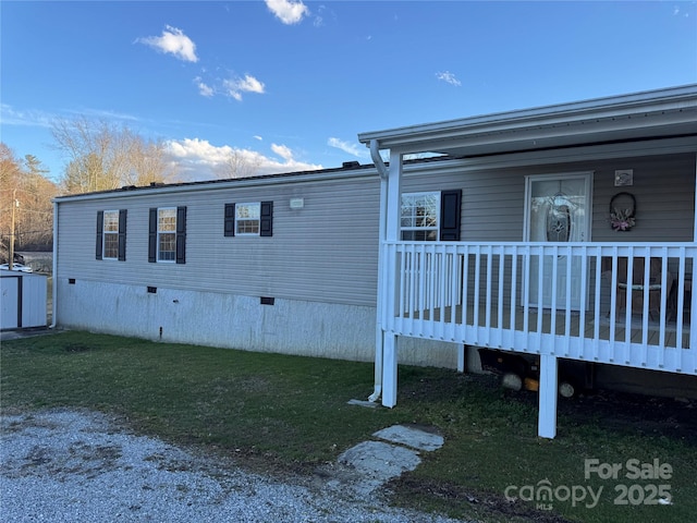 view of side of property with crawl space and a lawn