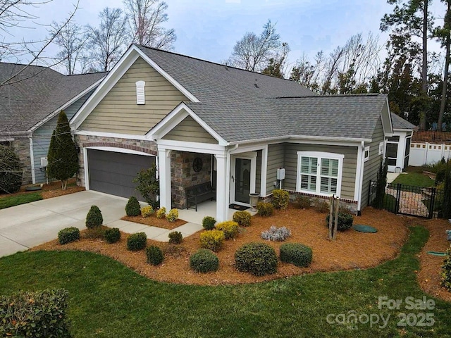 view of front of property featuring a shingled roof, concrete driveway, fence, and stone siding