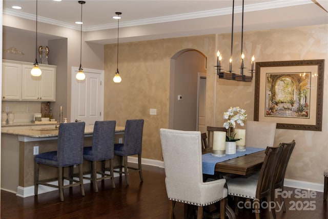 dining space featuring ornamental molding, arched walkways, dark wood-style flooring, and baseboards