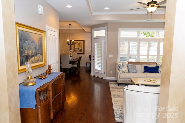 living area featuring recessed lighting, dark wood-type flooring, baseboards, a tray ceiling, and crown molding