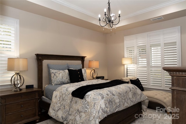 bedroom featuring a chandelier, a tray ceiling, ornamental molding, and visible vents