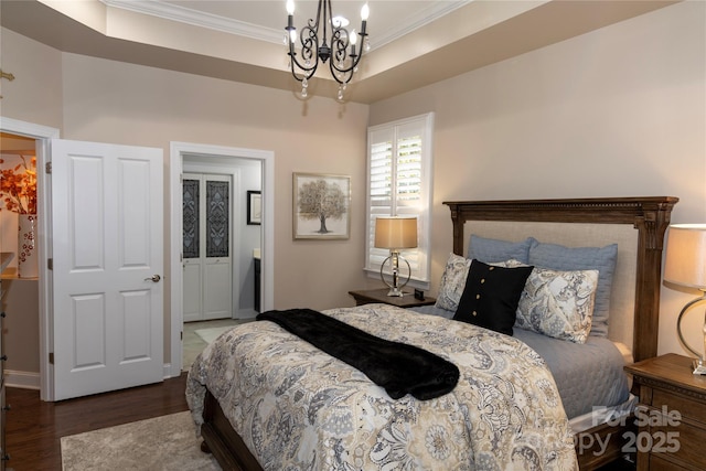 bedroom featuring a notable chandelier, ornamental molding, a raised ceiling, and wood finished floors