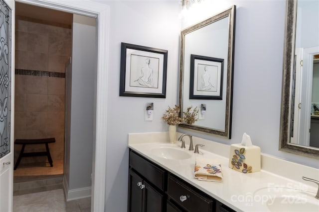 full bathroom featuring tile patterned flooring, a tile shower, and vanity