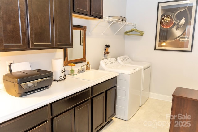 laundry area featuring cabinet space, baseboards, separate washer and dryer, and a sink