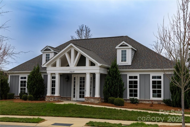 view of front of property with french doors, board and batten siding, a shingled roof, and a front lawn