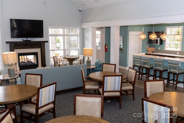 dining space featuring lofted ceiling, decorative columns, and a multi sided fireplace