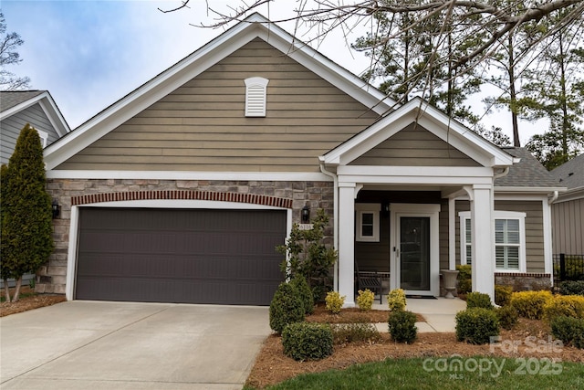 craftsman-style home with an attached garage, concrete driveway, roof with shingles, and stone siding