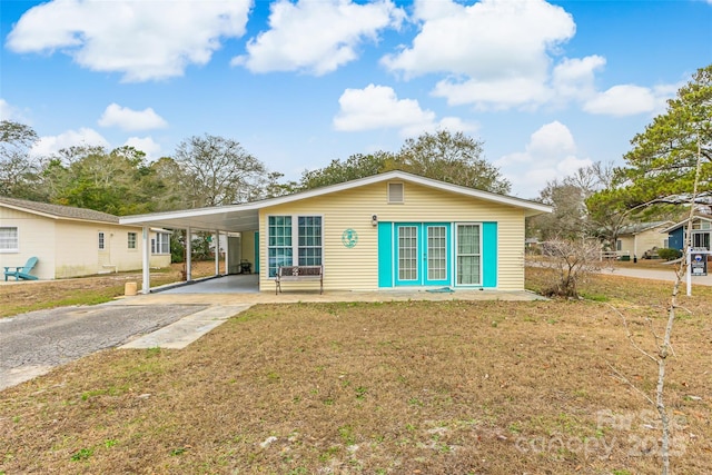 rear view of house featuring driveway, a lawn, and a carport