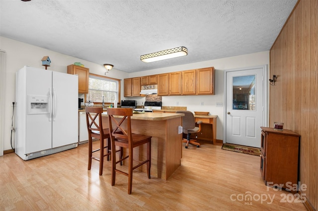 kitchen featuring under cabinet range hood, electric range, white fridge with ice dispenser, and light wood-style flooring