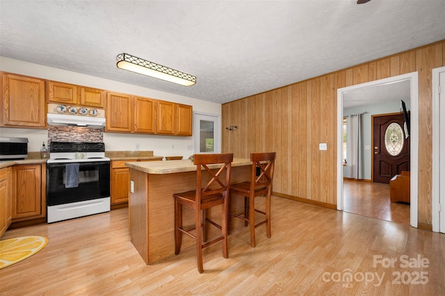 kitchen featuring electric stove, light countertops, light wood-type flooring, stainless steel microwave, and custom range hood