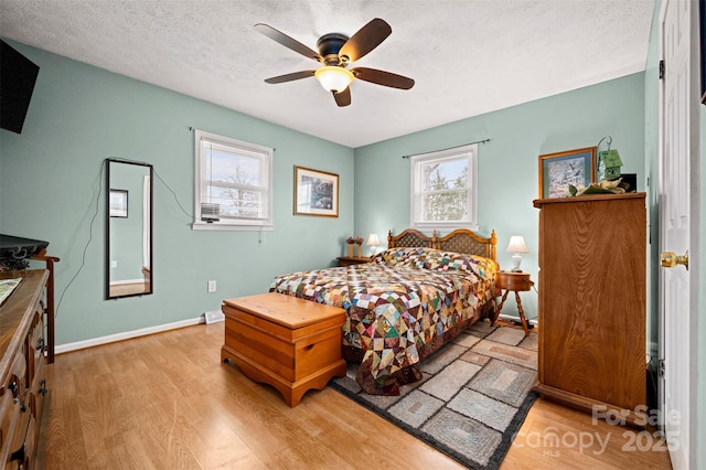 bedroom with light wood-type flooring, ceiling fan, a textured ceiling, and baseboards