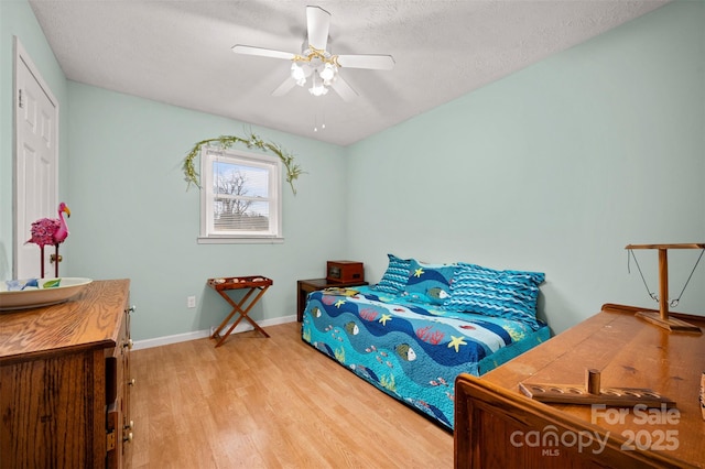 bedroom featuring light wood-type flooring, ceiling fan, a textured ceiling, and baseboards