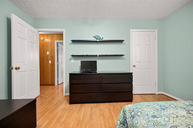 bedroom featuring a textured ceiling, light wood finished floors, and baseboards