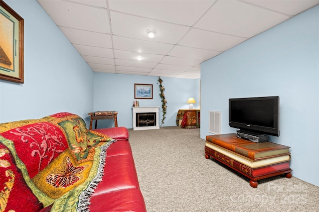 carpeted living room featuring a fireplace, visible vents, and a drop ceiling