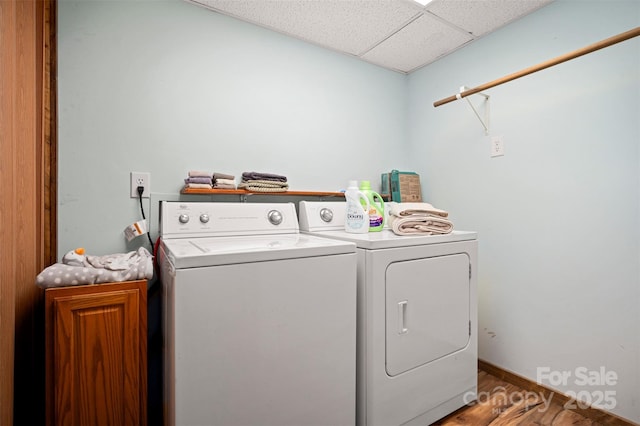 clothes washing area with washer and dryer, cabinet space, baseboards, and wood finished floors