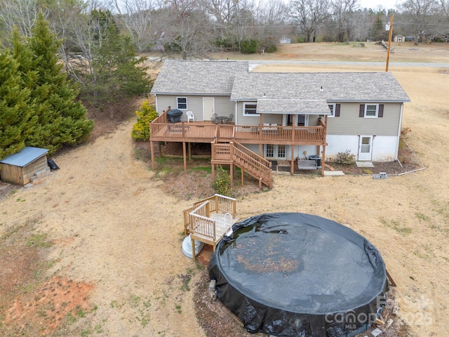 rear view of property with a deck, a shingled roof, and stairway