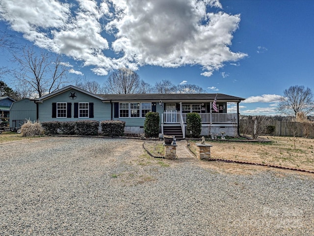 view of front of house featuring a porch, crawl space, and gravel driveway