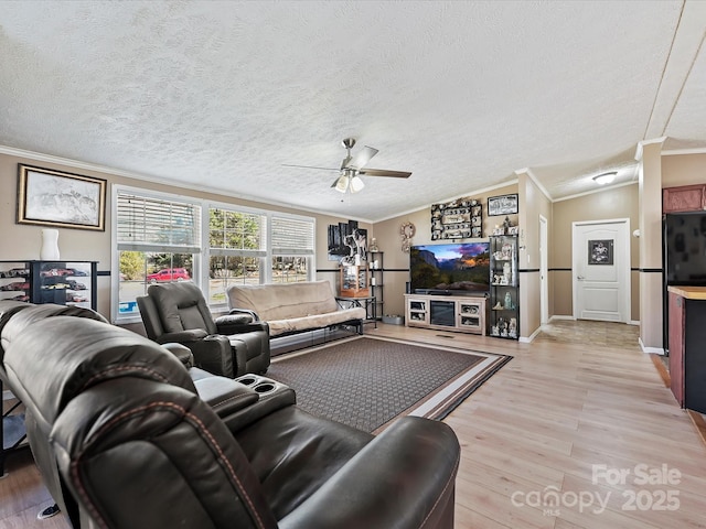 living room featuring ceiling fan, a textured ceiling, baseboards, light wood-style floors, and crown molding