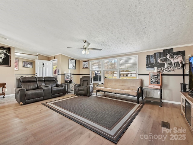 living room with crown molding, a textured ceiling, baseboards, and wood finished floors