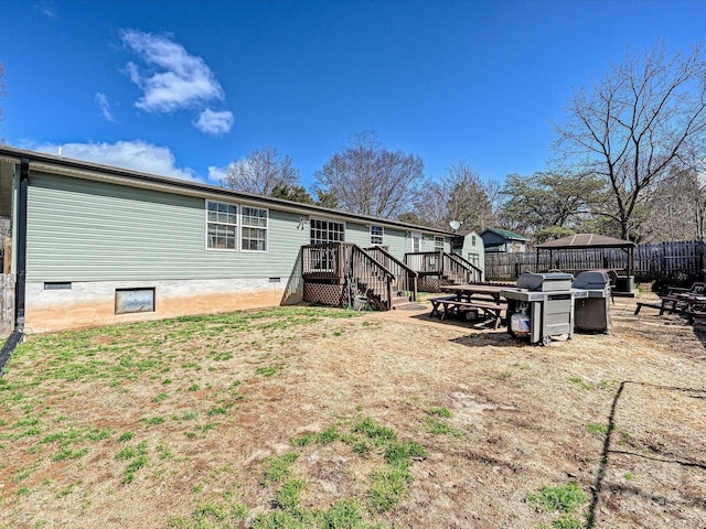 rear view of property with crawl space, fence, and a wooden deck