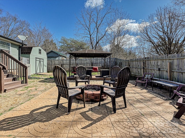 view of patio / terrace featuring an outbuilding, a fenced backyard, a fire pit, a gazebo, and a shed