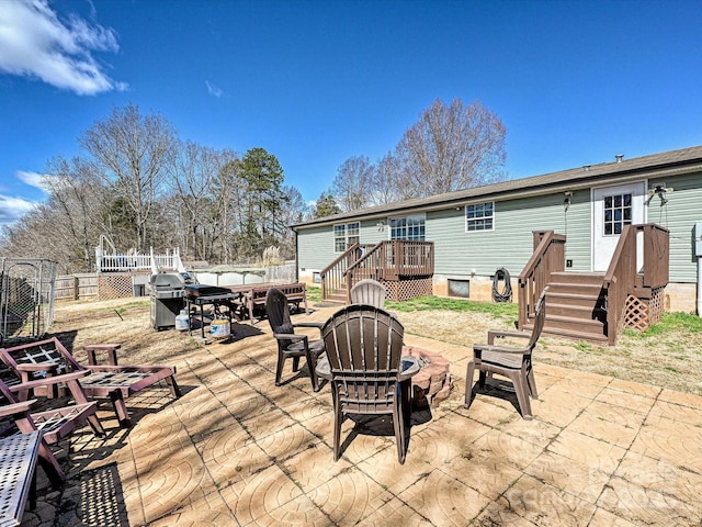 view of patio / terrace with a fire pit, a wooden deck, and fence